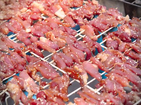 Raw beef or pork meat mixed with sesame dried by sun. Traditional food on street food market in Bangkok. Thailand.の写真素材