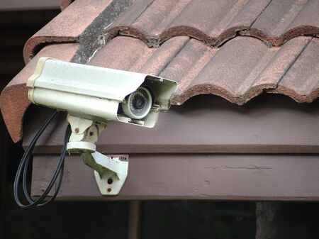 Old security camera or CCTV installed on the house roof. (security, safety, technology)の写真素材