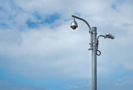 360 Degree fish eye dome CCTV and CCTV camera are installed on column against blue sky.の写真素材