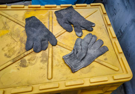 Old cloth gloves for craftsmanship on a yellow toolbox. Safety equipment for technicians