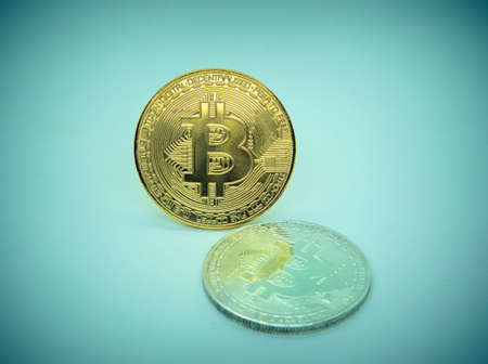 Golden coins of bitcoin cryptocurrency digital bit coin BTC currency on blue background.