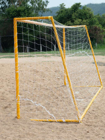 Yellow soccer goal on sandy field in rural area.の写真素材