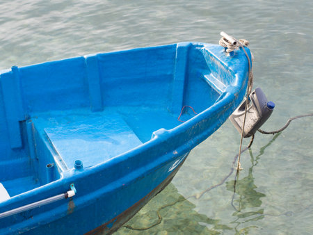 Small blue fishing boat docked in the harbor.の写真素材
