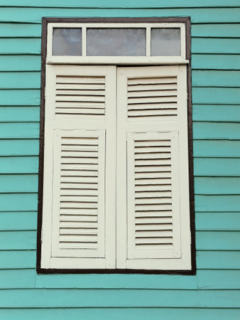 Window with white shutters on a blue wooden wall.の写真素材
