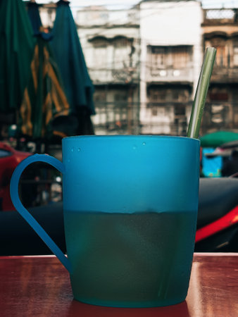 Blue Mug of Drink with Straw on a Red Table at an Outdoor Market.の写真素材