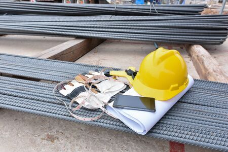 Yellow helmet, measuring tape  and blueprint on rebar ath the construction siteの写真素材