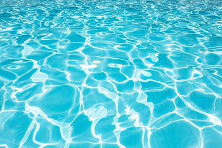Beautiful blue water surface in swimming pool with sun reflection for background