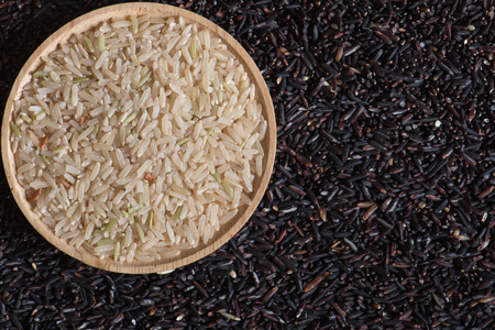 Closeup brown rice in wooden bowl on black berry rice backgroundの写真素材