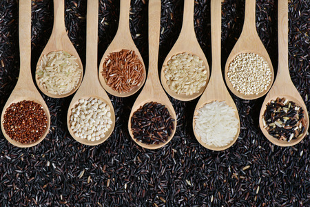 Top view different rice on wooden scoop with black riceberry background, Various rice organic on wooden spoon collectionの写真素材
