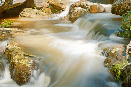 Closeup turbid water at the waterfall with stone slide and dangerの写真素材
