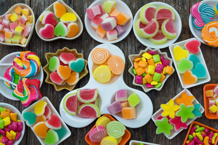 Various colorful sugary candy in container on old wooden plank, Different candy in contauner on old plank for party buffetの写真素材