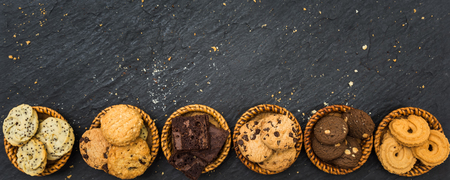 Top view different cookies on table top, Flat lay of various cookies on black stone for background, Prepared cookies food buffet on table for serveの写真素材