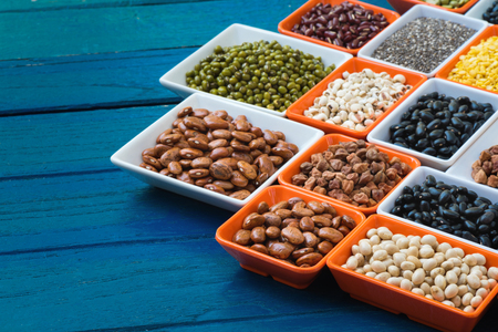 Different dry legumes in containeron blue plank, Multicolor dried beans for eating healthyの写真素材