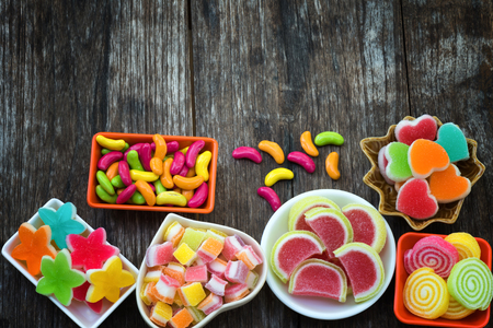 Various colorful sugary candy in container on old wooden plankの写真素材