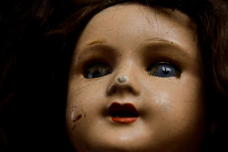 Closeup of an old damaged doll. Shallow DOF, focus on the eyes. High contrast.の写真素材