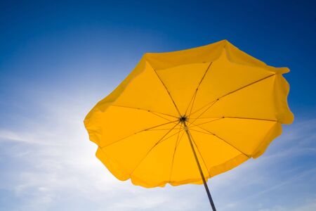 A yellow sunshade against a deep blue sky.の写真素材
