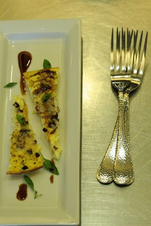 An egg dish with sauce and basil on a white plate and two forks.の写真素材