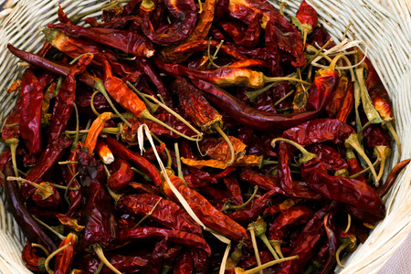 A white basket holding some dried chillie peppers.