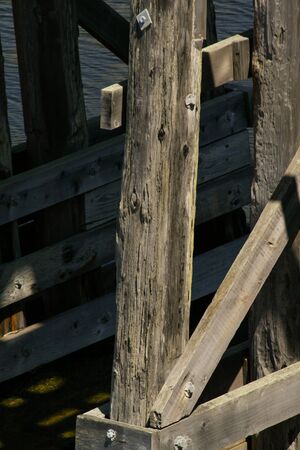 A wooden structure above a body of water with the sun casting shadows on it.の写真素材