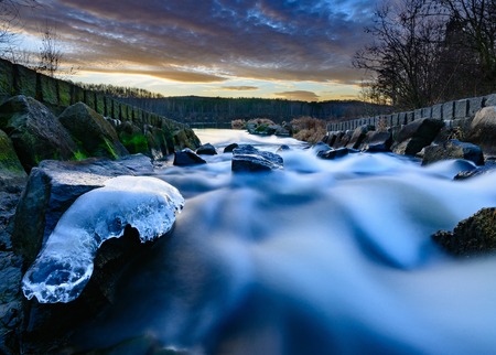 Sunset over wild blurred water with frozen stoneの写真素材