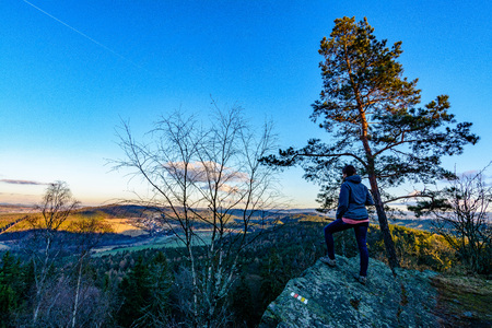 Woman enjoying clear view of autumn sunset at the edge of rock.の写真素材