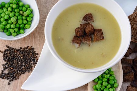 Green pea soup in a bowl with bread and sour creamの写真素材