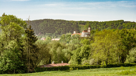 Scenic spring landscape with leafy green woodland and a view to a distant historic church or cathedral over the treetopsの写真素材
