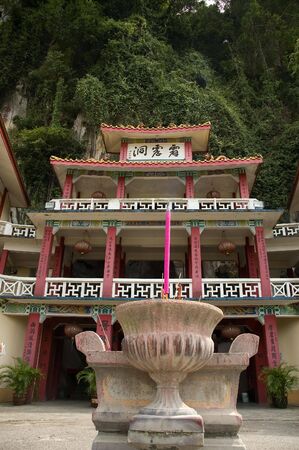 A buddhist temple located in a cave in the background and a shrine in the foregroundの写真素材