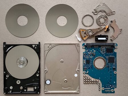 A dismantled hard disk drive laid out neatly showing all its componentsの写真素材
