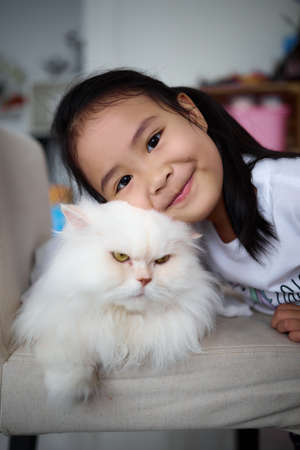 A girl takes a picture with her favorite white cat. Asian children hugging white cats.の写真素材