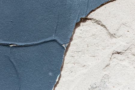 cracked blue painted plaster peeling off a wall