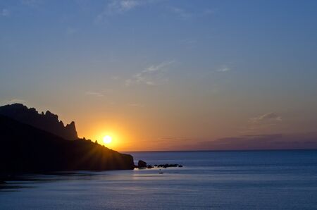 View of the sunrise over the mountain above the seaの写真素材