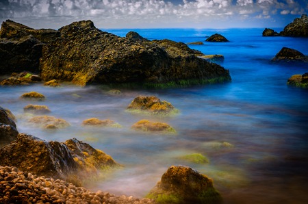 Overgrown with algae and mud stones washed by sea water  A slow shutter speed の写真素材