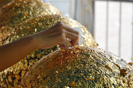 Buddhism put gold leaf on round stoneの写真素材