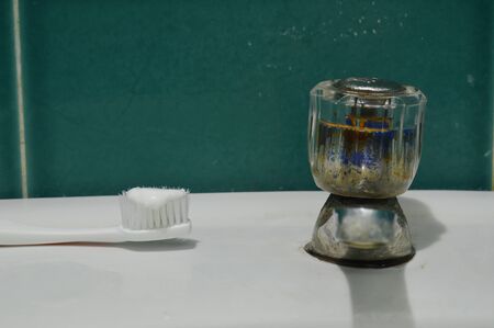 toothpaste on toothbrush and old faucet on white sink bathroom