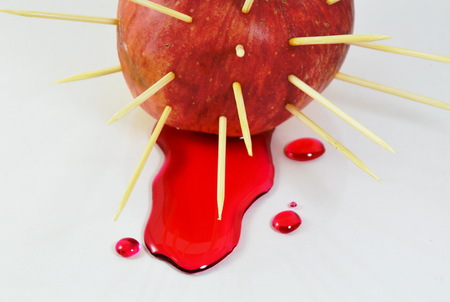 red apple stab by toothpicks and red liquid flowの写真素材