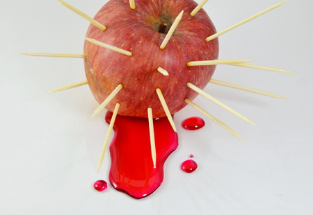toothpicks stab into red apple and red liquid flowの写真素材
