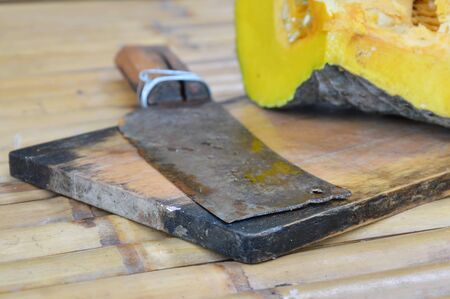old chop knife and pumpkin on wooden chop blockの写真素材