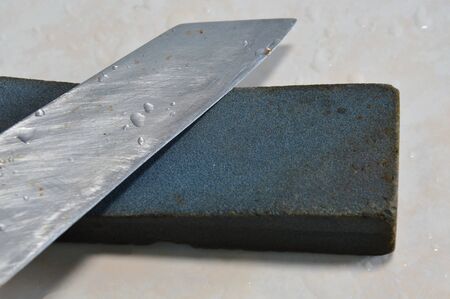 kitchen knife and whetstone on tile floorの写真素材
