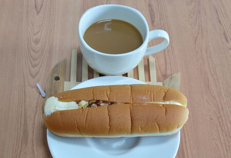hot dog bread filled cream almond and coffee on wooden dish plateの写真素材