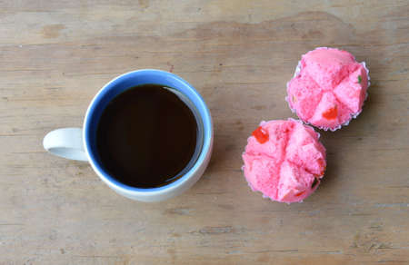 black coffee cup and pink dessert trolley on wooden tableの写真素材