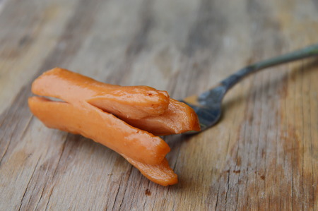 hot dog stab in fork on wooden boardの写真素材