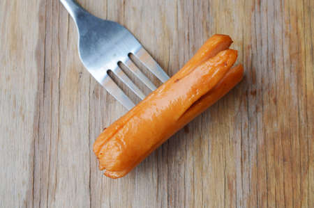 hot dog stab in fork on wooden board