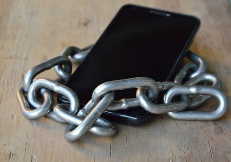 chain roll over smart phone on wooden boardの写真素材