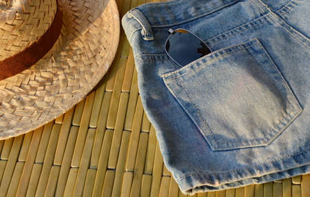 woven hat and sunglasses in blue jean pocket under sunlightの写真素材
