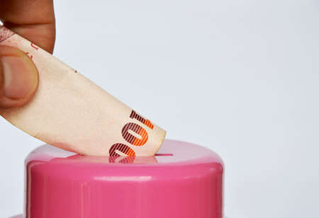 finger drops Thai banknote in pink piggy bankの写真素材