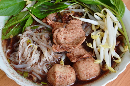 thin noodle with pork ball in brown soup on bowl