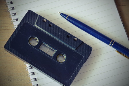 audio cassette tape recorder and blue pen on book