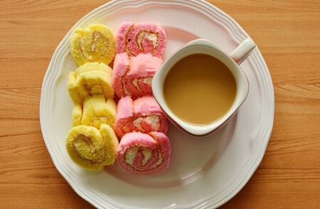 mini strawberry and vanilla jam roll with coffee on dish