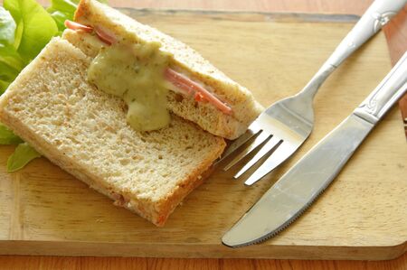 pork bologna whole wheat sandwich with fork and knife on wooden chop blockの写真素材